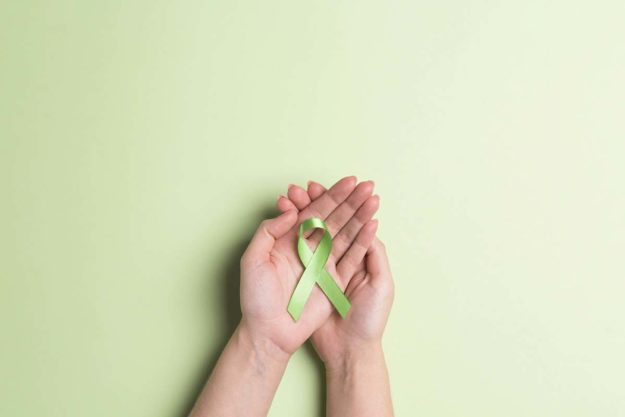 Recognizing World Mental Health Day in October a green ribbon represents world mental health day