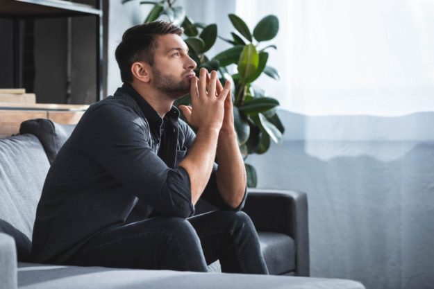 Tips for Avoiding Your Anxiety Triggers person on couch dealing with anxiety triggers